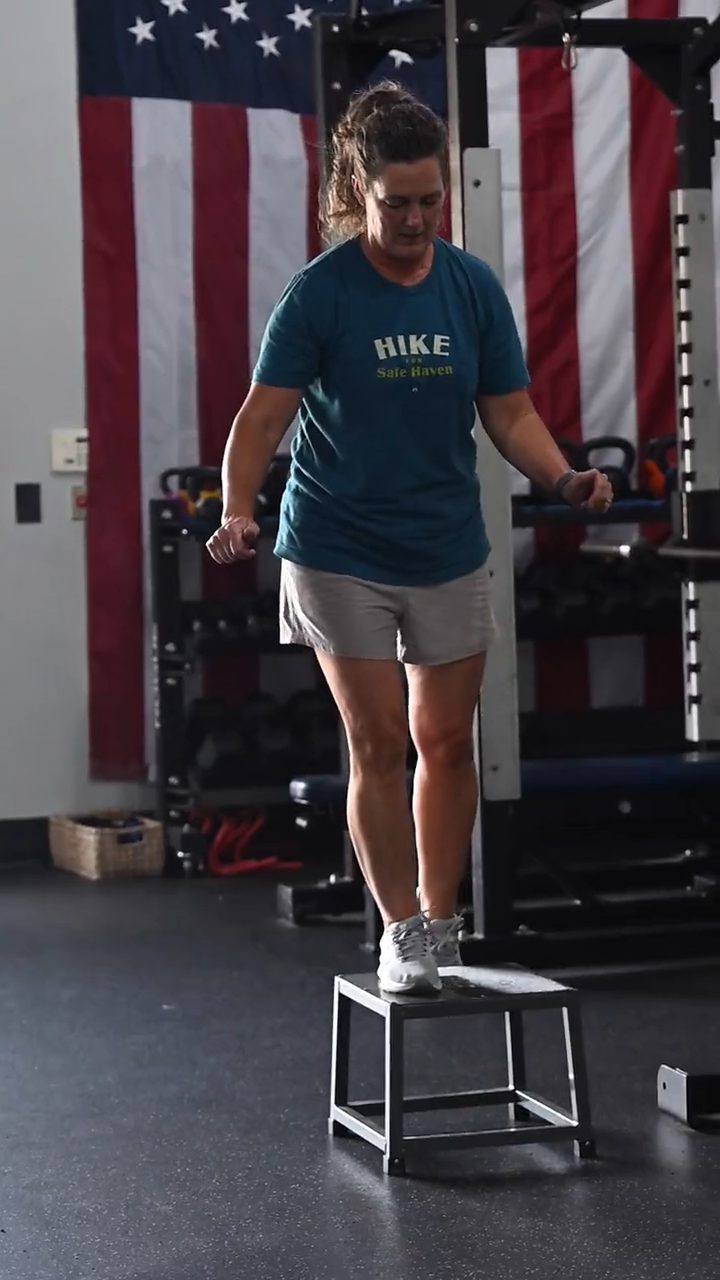 A client stepping down off a low box in front of the US flag